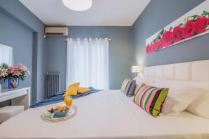 Glyfada's Central Apartment في أثينا: غرفة نوم بها سرير أبيض مع وعاء من الفواكه عليها
