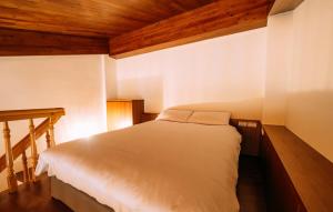 a bedroom with a white bed with wooden ceilings at 中央旅社 in Magong