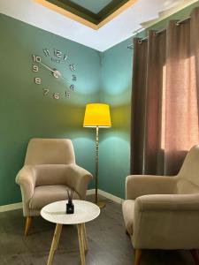 una habitación con dos sillas y un reloj en la pared en AL BON Park, en Berat