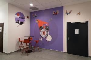 a purple wall with a clock and two stools at Equity Point Budapest in Budapest