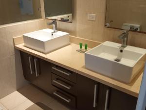 a bathroom counter with two sinks and a mirror at Playa Blanca Apartamentos in Río Hato