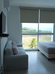 uma sala de estar com um sofá e uma grande janela em Playa Blanca Apartamentos em Río Hato