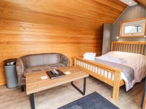 Habitación con cama, sofá y mesa. en Willow Lodge At Bridge Lake Farm & Fishery en Banbury