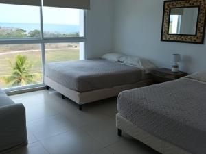 a bedroom with two beds and a large window at Playa Blanca Apartamentos in Río Hato