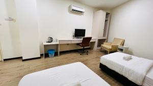 Pokój z 2 łóżkami i biurkiem z komputerem w obiekcie Seeds Hotel Cheras Taman Bukit Segar w mieście Cheras