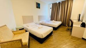 a hotel room with two beds and a couch at Seeds Hotel Cheras Taman Bukit Segar in Cheras