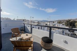 uma varanda com cadeiras e uma mesa no telhado em She Mykonos - Luxury Apartments em Míconos