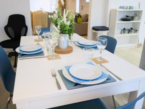 a white dining table with plates and glasses on it at Elegant home mod kitchen, fast Wi-Fi, free parking in Carrickfergus