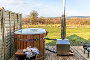 Morgan Sweet, Apple Tree Glamping, Nr Wells في ويلْزْ: يوجد حوض استحمام ساخن على سطح السفينة بجوار شواية