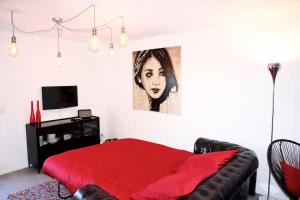Un dormitorio con una cama roja y una pintura en la pared en Beau studio dans ancienne grange rénovée., en Blonay
