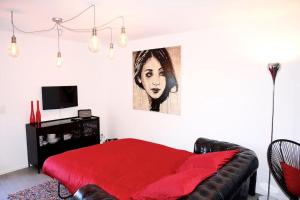 a bedroom with a red bed and a painting on the wall at Beau studio dans ancienne grange rénovée. in Blonay