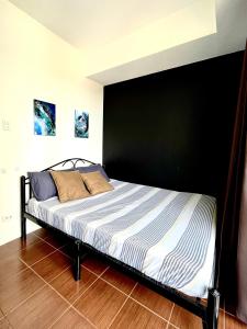 a bed in a bedroom with a black wall at Mey’s Condo in Pasig - 1BR with Balcony in Manila