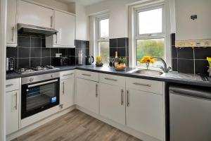 a kitchen with white cabinets and a sink at Finest Retreats - Smithfields in Llanrwst