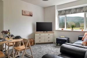 a living room with a tv and a couch and a table at Finest Retreats - Smithfields in Llanrwst