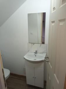 a white bathroom with a sink and a mirror at La Miruna in Comăneşti