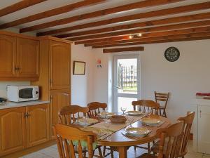 eine Küche mit einem Holztisch mit Stühlen und einer Mikrowelle in der Unterkunft Greenrigg Cottage in Caldbeck