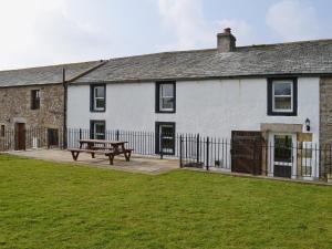 ein weißes Gebäude mit einer Bank davor in der Unterkunft Greenrigg Cottage in Caldbeck