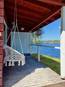 a swing on the porch of a house overlooking the water at Hotelli Hirsiranta in Ruokolahti