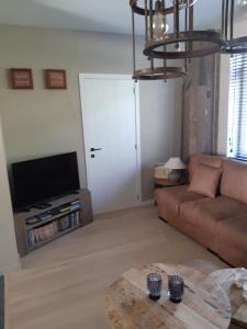 uma sala de estar com um sofá e uma televisão em Het Helmgras em Middelkerke
