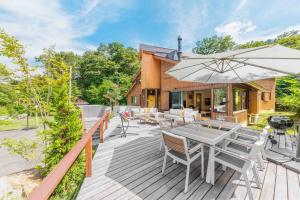 une terrasse en bois avec une table et un parasol dans l'établissement Sakura 88 - Luxury Villa - 280sqm 4 bedrooms, à Hakuba