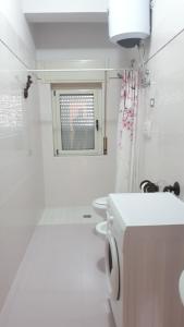 baño blanco con lavadora y ventana en Villa Ginevra en Paestum
