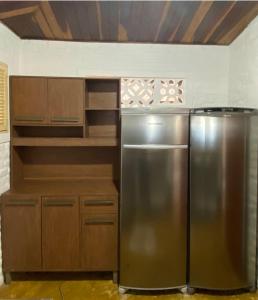 a kitchen with a stainless steel refrigerator and wooden cabinets at Casa Pé na Areia Maracajau in Maxaranguape