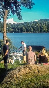 Évika boutique hotel في Eskilsby: مجموعة من الناس يجلسون حول طاولة نزهة بالقرب من البحيرة