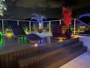 a rooftop deck with two chairs and palm trees at night at Mariscal Praia Centro Vista al Mar Departamento de Lujo in Canto Grande
