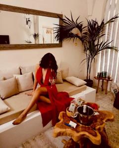 Amira 1899 Luxury Suite في غالاتينا: امرأة ترتدي ثوب احمر تجلس على سرير