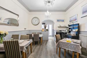 a dining room with tables and chairs and a clock on the wall at Cherwood Guest House in Paignton