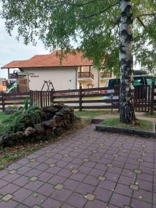 einen Park mit einem Baum, einem Zaun und einem Spielplatz in der Unterkunft Gočke Lux vile & Duplex in Vrnjačka Banja