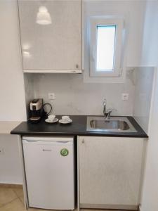 a small kitchen with a sink and a refrigerator at Celeste Apartments in Ornos