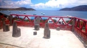 ein roter Zaun mit Booten im Wasser in der Unterkunft TITI QALA HOSTEL in Comunidad Challapampa