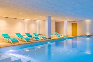 - une piscine avec des chaises bleues dans la chambre dans l'établissement Best Western Plus Hôtel Escapade Senlis, à Senlis