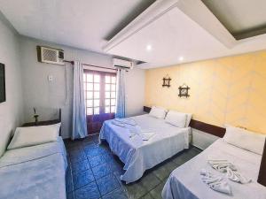a hotel room with two beds and a window at Hotel Pousada Mahon Mar in Praia do Frances