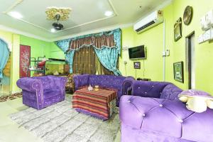 a living room with purple couches and a tv at OYO 90740 Paddington Lodge in Kota Bharu
