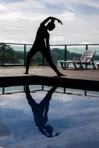 een vrouw die een yoga pose doet naast een zwembad bij Vista Espetacular em Escarpas com Piscina in Capitólio