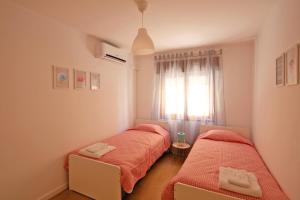 two beds in a room with a window at Apartamento SofiSara in Tavira
