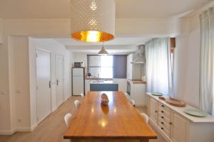 a dining room with a wooden table and a kitchen at Apartamento SofiSara in Tavira