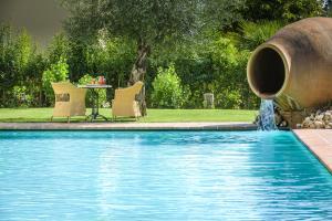 una piscina con una fuente y una mesa en Hotel San Gregorio, en Pienza