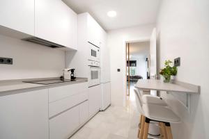 a white kitchen with a counter and a table at MARIA DEL MAR SEA APARTMENT in Chiclana de la Frontera