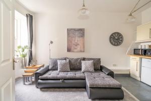 ein Wohnzimmer mit einem Sofa und einer Uhr an der Wand in der Unterkunft Charming 1 Bedroom Apartment - Edinburgh in Edinburgh