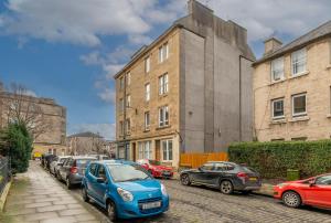 eine Reihe von Autos, die auf einer Straße neben Gebäuden geparkt sind in der Unterkunft Charming 1 Bedroom Apartment - Edinburgh in Edinburgh