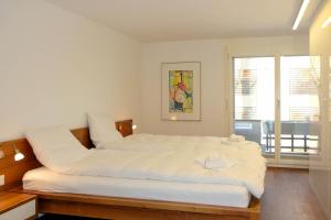 een groot wit bed in een kamer met een raam bij Buchtoase in Spiez