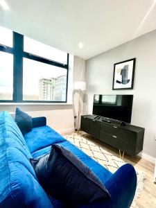 sypialnia z niebieskim łóżkiem i telewizorem z płaskim ekranem w obiekcie Stylish studio apartment near to Old Trafford stadium w Manchesterze