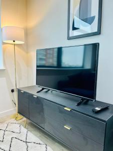 een zwart entertainmentcentrum met een flatscreen-tv bij Stylish studio apartment near to Old Trafford stadium in Manchester