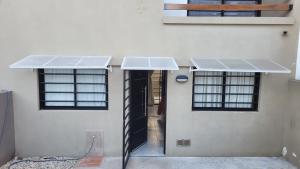 - un bâtiment blanc avec deux fenêtres et une porte dans l'établissement Departamento Santa Teresita, à Santa Teresita