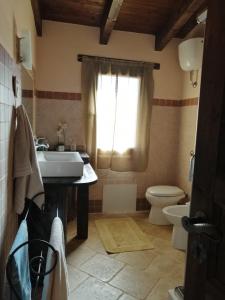 ein Bad mit einem Waschbecken, einem WC und einem Fenster in der Unterkunft Alex's Apartment in Iglesias