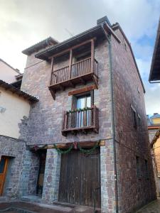 a brick building with a wooden door and a balcony at Ático Dúplex en Laspaúles in Laspaúles