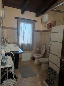 baño con lavabo y aseo y ventana en Alex's Apartment en Iglesias